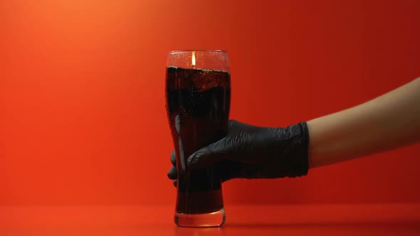 Hand Puts Glass of Soda, Refreshing Beverage Rich in Sugar, High Calorie Drink