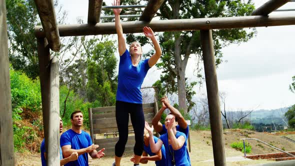 Fit woman climbing monkey bars while fit people cheering 4k