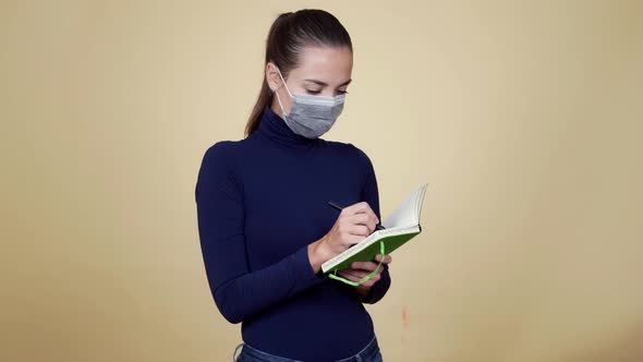 Portrait of Young Woman in Protective Medical Mask Writes in Diary, Isolated