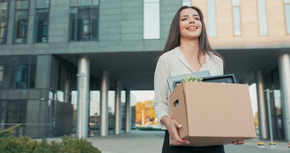 Atractive Beautiful Smiling Brunette in a Shirt Stands in Front of a Glass Modern Company Building