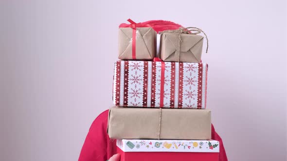 Bewildered Little Girl Peeking Out From Behind a Pile of Gifts on White Background