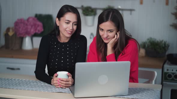 Bored Young Female Friends Watching Video on Laptop at Home, Discussing It