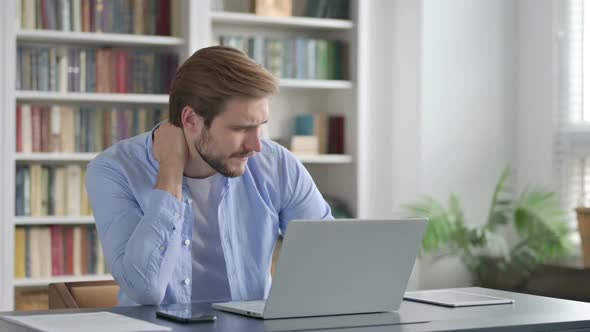 Man Having Neck Pain While Typing on Laptop