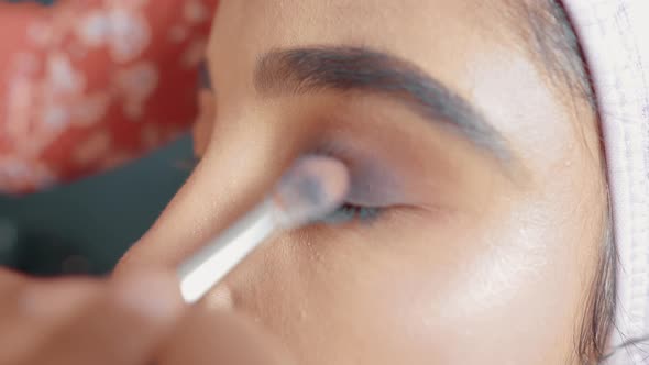 Close up of make up artist putting a eye shadow with make up brush on woman's eyes and doing the mak