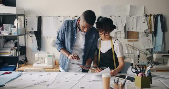 Man and Woman Clothes Designers Using Tablet Drawing Sketches in Studio