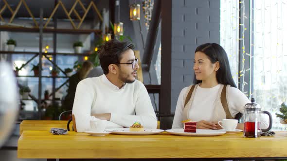 Young Diverse Couple Having Tea and Dessert in Cafe and Chatting