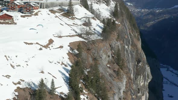 aerial of Paraglider jumping of edge of mountain near beautiful Swiss town - HD crop