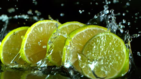 Super Slow Motion Shot of Fresh Lime Slices Falling Into Water Isolated at 1000 Fps.