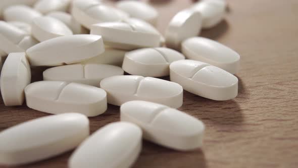 White oval tablets on a wooden surface close-up. Healing pills