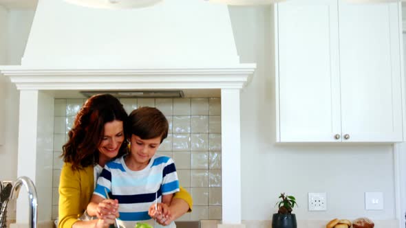 Mother and son mixing the salad in kitchen