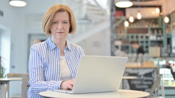 Laptop Use By Creative Old Woman Looking at Camera in Cafe