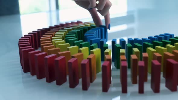 Line up of Dominoes in Rainbow Falling Colors with LGBT Colors of a Hand