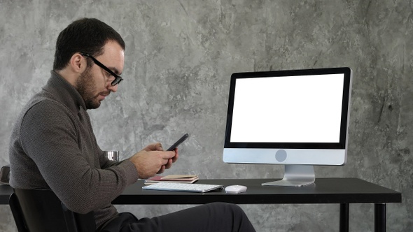 Businessman looking at his smartphone messaging and sitting