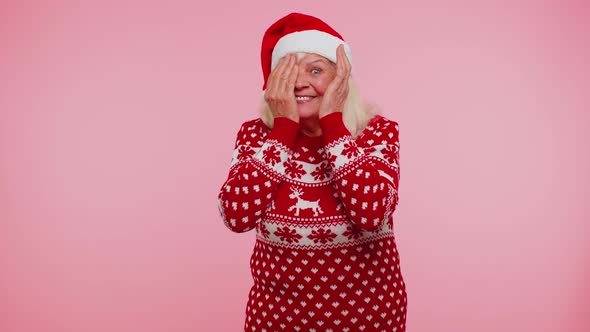 Woman in Sweater Santa Christmas Hat Fooling Around Having Closing Eyes with Hand and Spying Through