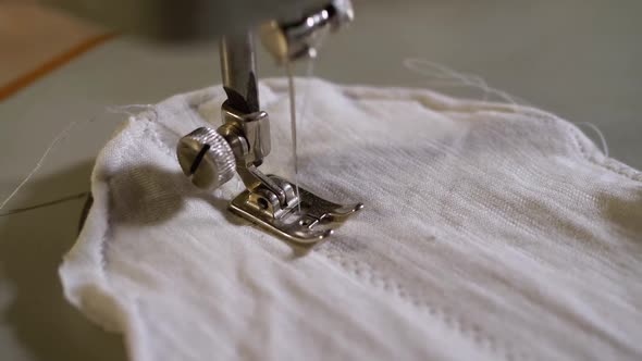 Sewing Machine Needle in Motion. A Tailor Sews Homemade Face Mask of Fabric