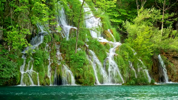 Lovely Waterfall with Many Cascades, Surrounded By Rich Green Flora, Flowing Into a Turquoise