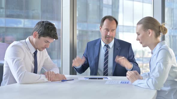 Angry Middle Aged Businessman Having Argument with Workers in Meeting