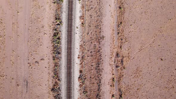Drone shot looking down on railroad tracks in the desert on a sunny day