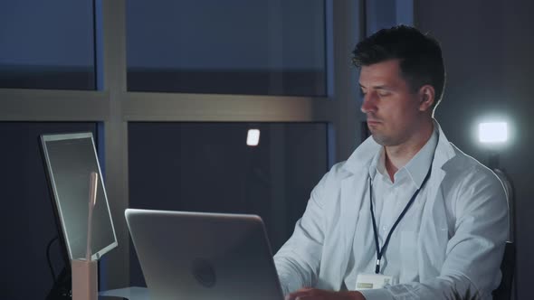 Male Specialist in Electronics Working on the Computer in Modern Lab. Professional Writing on