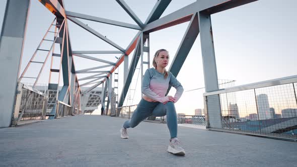 Concentrated Young Caucasian Woman Do Reverse Lunge Exercise on Bridge