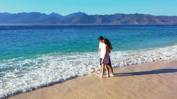 Happy man and woman on romantic honeymoon enjoy life on beach on clean white sand background 