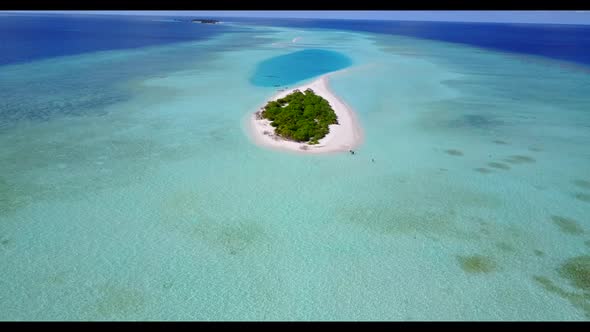 Aerial drone shot sky of idyllic seashore beach voyage by shallow water and white sandy background o