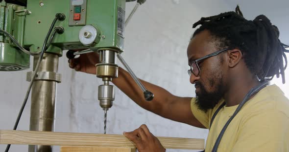 Carpenter drilling wooden plank with machine in workshop 4k