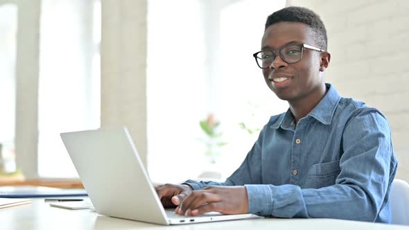 Positive Young African Man with Laptop Smiling at Camera