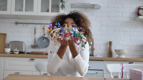 African Woman Holds in Hands and Blows Decorative Confetti