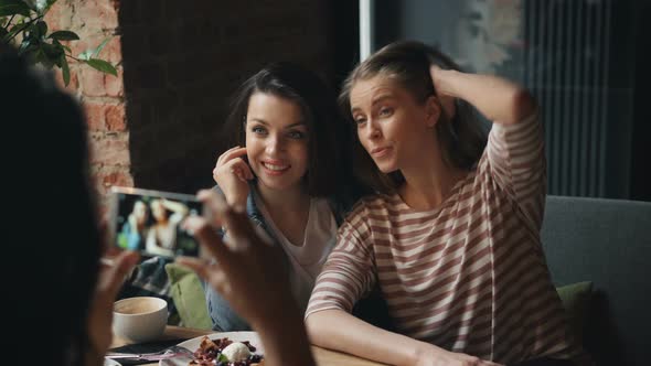 Attractive Young Women Taking Photo in Diner Posing Looking at Smartphone Camera