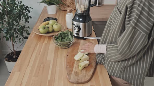 Muslim Woman Putting Apple in Blender while Cooking in Kitchen