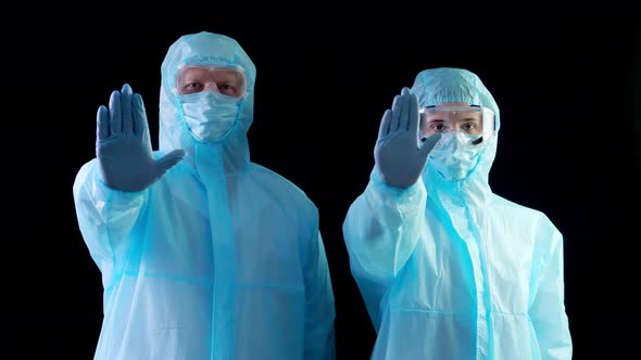 Doctor, Nurse in Special Protective Suits, Masks, Goggles, Looking at Camera, Showing Stop Sign By