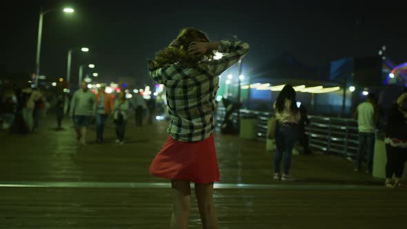 Young woman spinning on Santa Monica Pier, at night