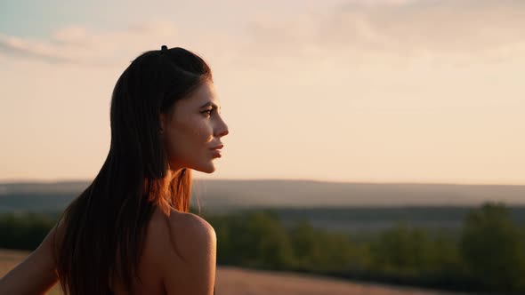 Portrait of a Beautiful Woman at Sunset in a Black Dress Poses Beautiful