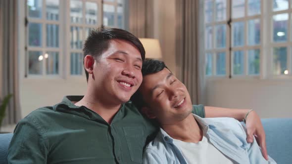 Happy Asian Gay Couple Watching Tv While Sitting On A Couch In Apartment. Adult Boyfriends Hug