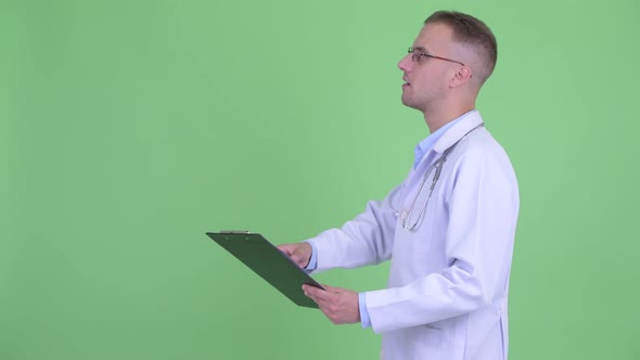 Profile View of Happy Handsome Man Doctor Reading on Clipboard