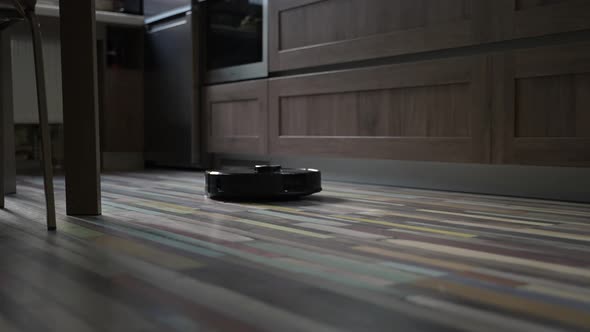 Robotic Vacuum Cleaner is Cleaning Floor of Modern Kitchen