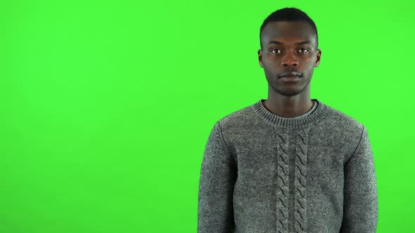 A Young Black Man Looks at the Camera and Taps the Watch on His Wrist - Green Screen Studio