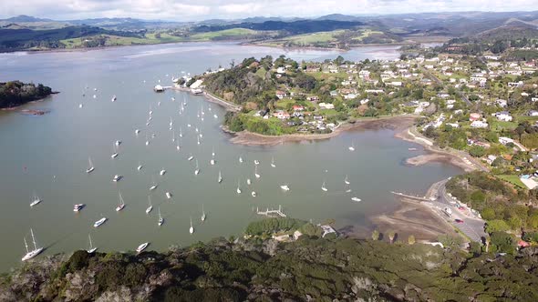 A lowering aerial drone shot of Mangonui town, harbour and boats on the Doubtless Bay in Northland,