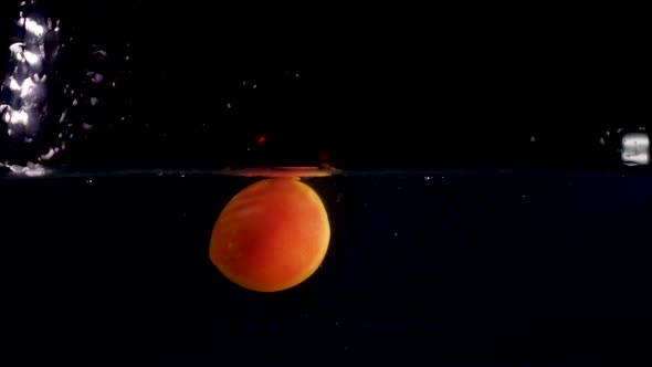 500-fps slow motion reverse video of a red tomato splashing into the water. Black background