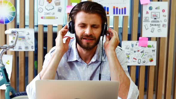 Executive listening to music while using laptop