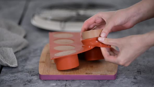 Woman makes homemade chocolate mousse cakes in a kitchen.