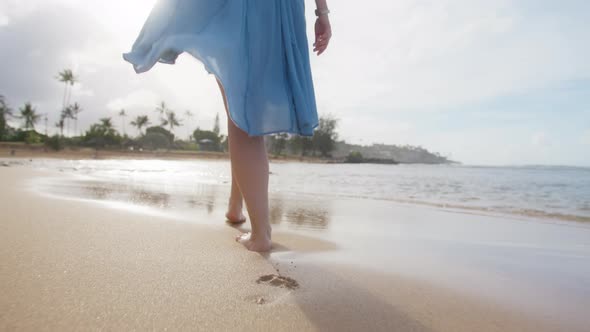 Close Up Woman in Flattering Blue Beach Dress Walking Barefoot By Sandy Beach