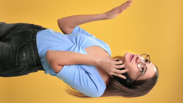 VERTICAL VIDEO POV Happy Modern Female Friendly Talking Use Smartphone Isolated on Orange Studio
