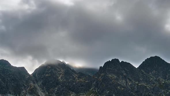 Dark Clouds Moving Fast over Rocky Alpine Mountain Peak