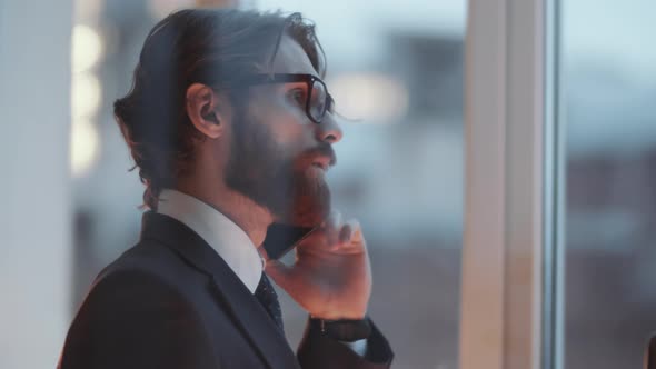 View through Glass Wall of Businessman Speaking on Mobile Phone