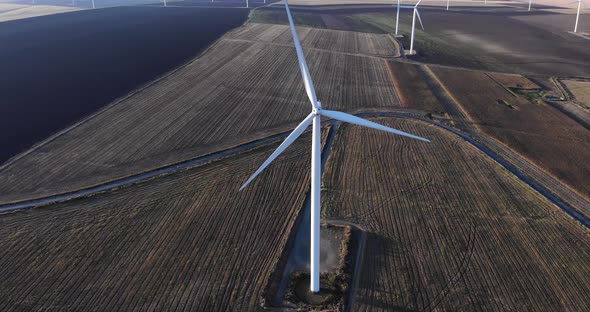 Wind Turbine Spinning At The Wind Farm On A Fine Weather. aerial tilt-up, pullback