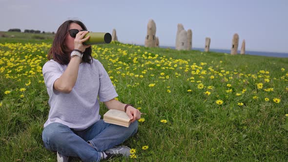 The Girl Drinks Tea Sitting on the Green Grass