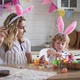 charming woman and her two-year-old son in bunny ears paint Easter eggs with paints - VideoHive Item for Sale