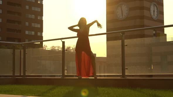 Beautiful Young Girl Dancing on the Street of a Modern City in the Sunset Light